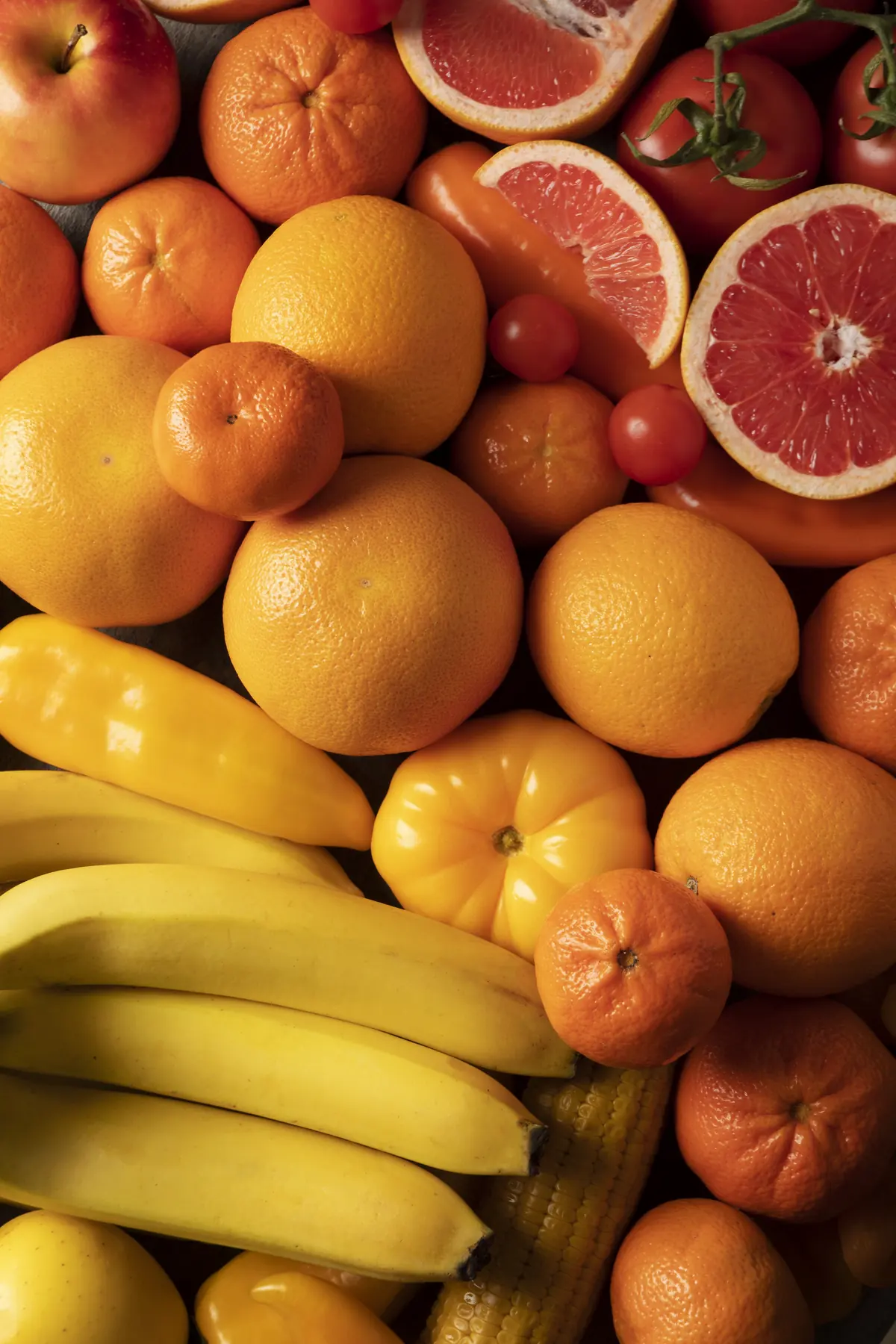 Naranjas, mandarinas, pomelo partido y plátanos colocados juntos
