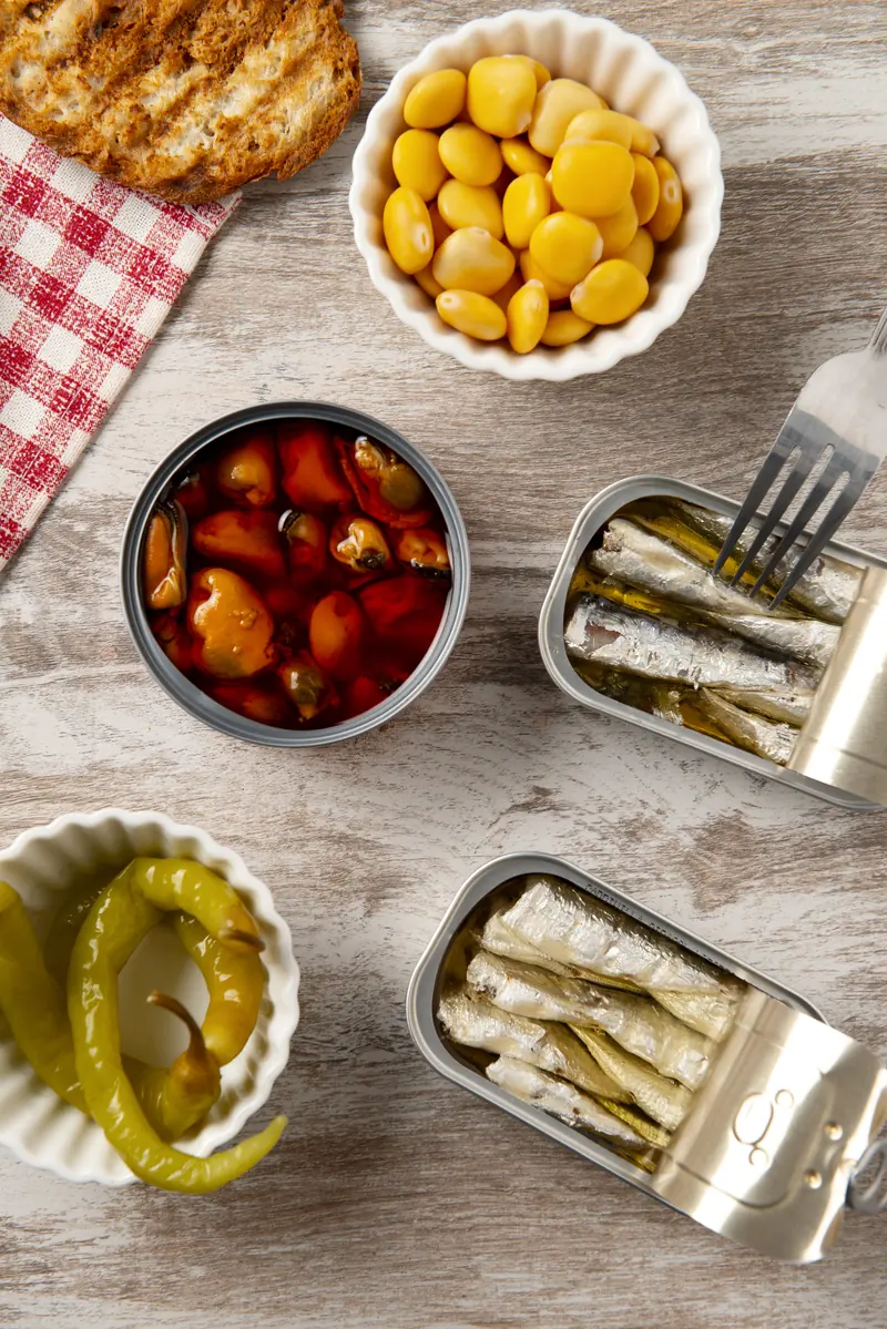 Latas de sardinas abiertas junto a altramuces y pan tostado