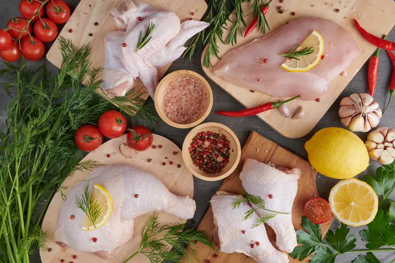 Piezas de pollo fresco sobre tablas de madera con romero y limón